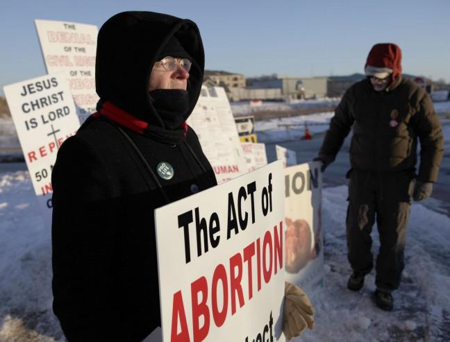 Anti-abortion activists hold up signs in protest of a proposal to allow second-trimester abortions at MSC.