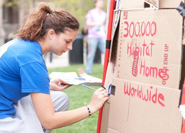 UW Habitat for Humanity members painted facts about world poverty on the sides of a cardboard shack built Friday on Library Mall. The organization\'s international parent has constructed more than 350,000 homes across the world since it was founded.