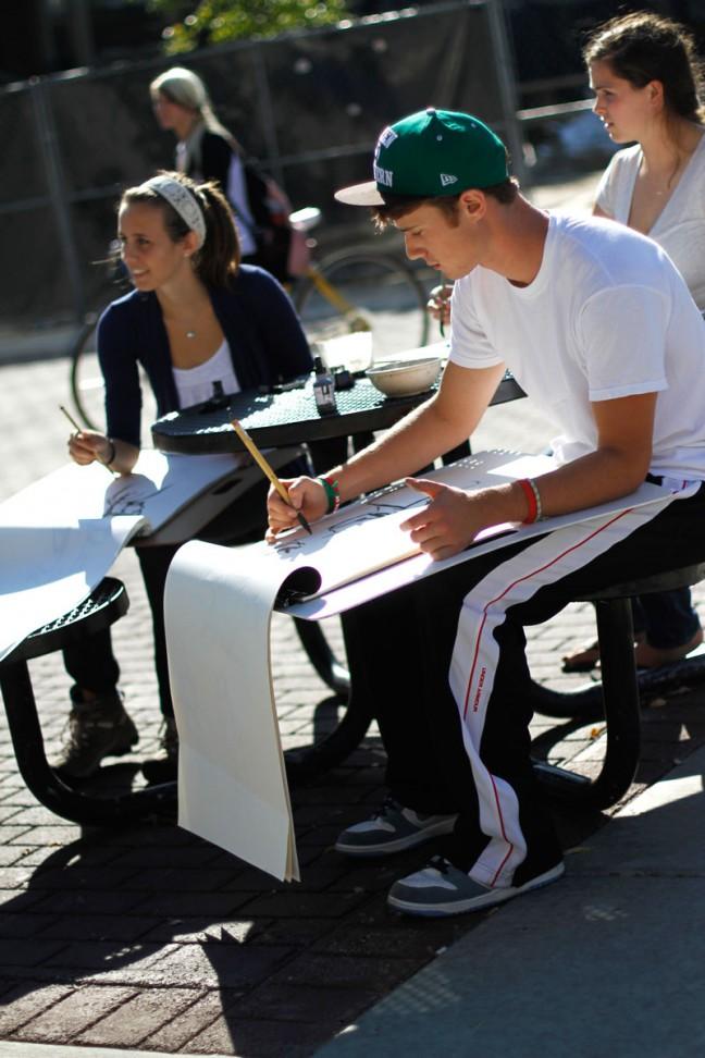 An introductory drawing class takes advantage of the warm weather and catches some rays on Monday. Students took a recess from damp classrooms and desks, making the picnic tables on Library Mall their art studio for the day.