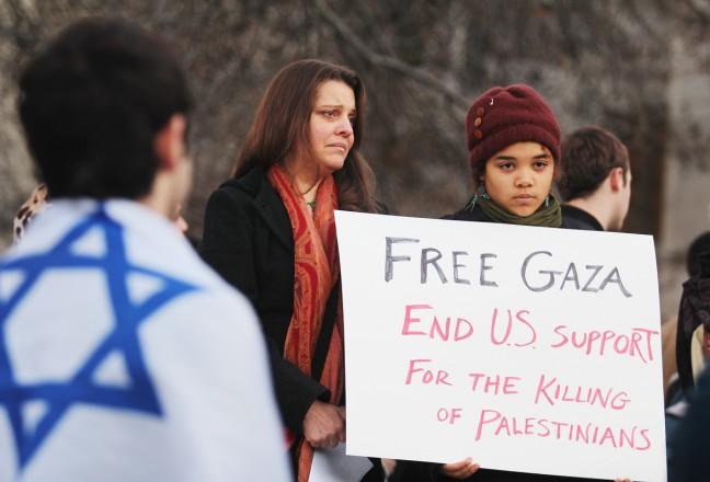 An Israel supporter looks on as a woman holds a sign in support of Palestine. The two rallies were held concurrently in 2012, with little to no dialogue or debate exchanged between the two.