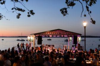 People gather and socialize in a recently-renovated section of seating at the Memorial Union Terrace at the University of Wisconsin-Madison as dusk falls to night following a spring sunset on June 2, 2016. In the background is the Terrace's new performance stage and Lake Mendota. (Photo by Jeff Miller/UW-Madison)