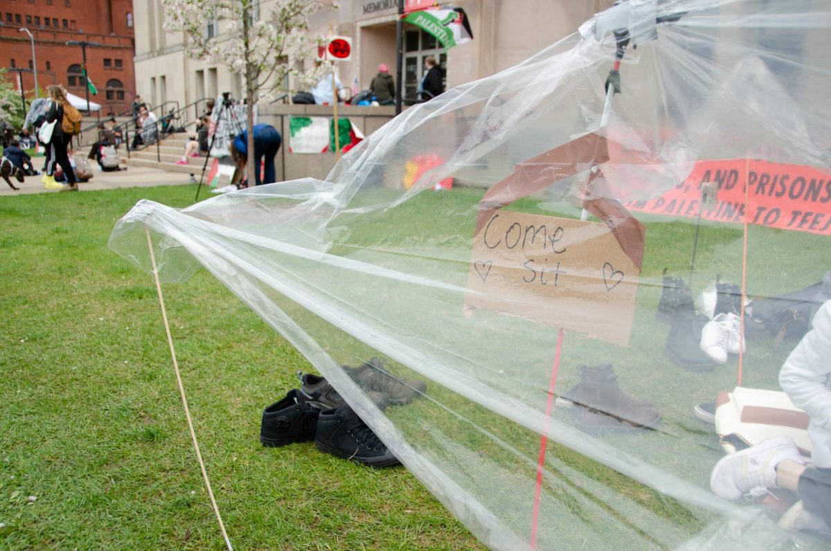 A sign invites demonstrators to come sit under a pitched sheet of plastic at Library Mall on May 2, 2024. 