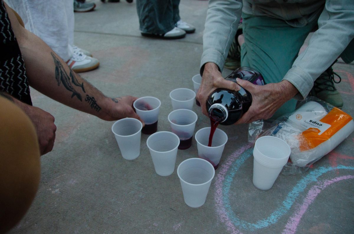 A demonstrator pours grape juice for others at the Liberation Shabbat at Library Mall on May 3, 2024. 