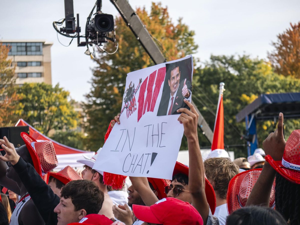 Student holds sign at the Fox Big Noon Kickoff event on the Kohl Center lawn. 