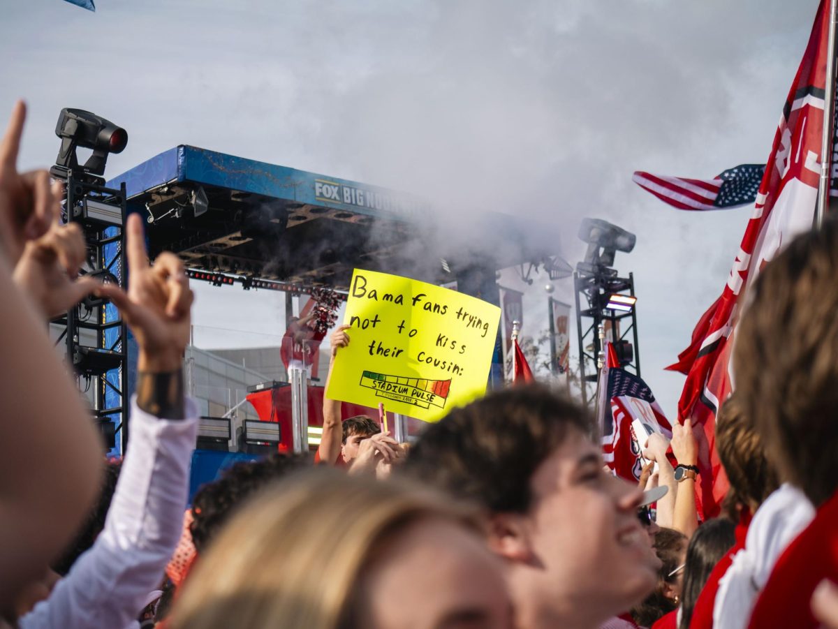 Student holds sign at the Fox Big Noon Kickoff event on the Kohl Center lawn. 