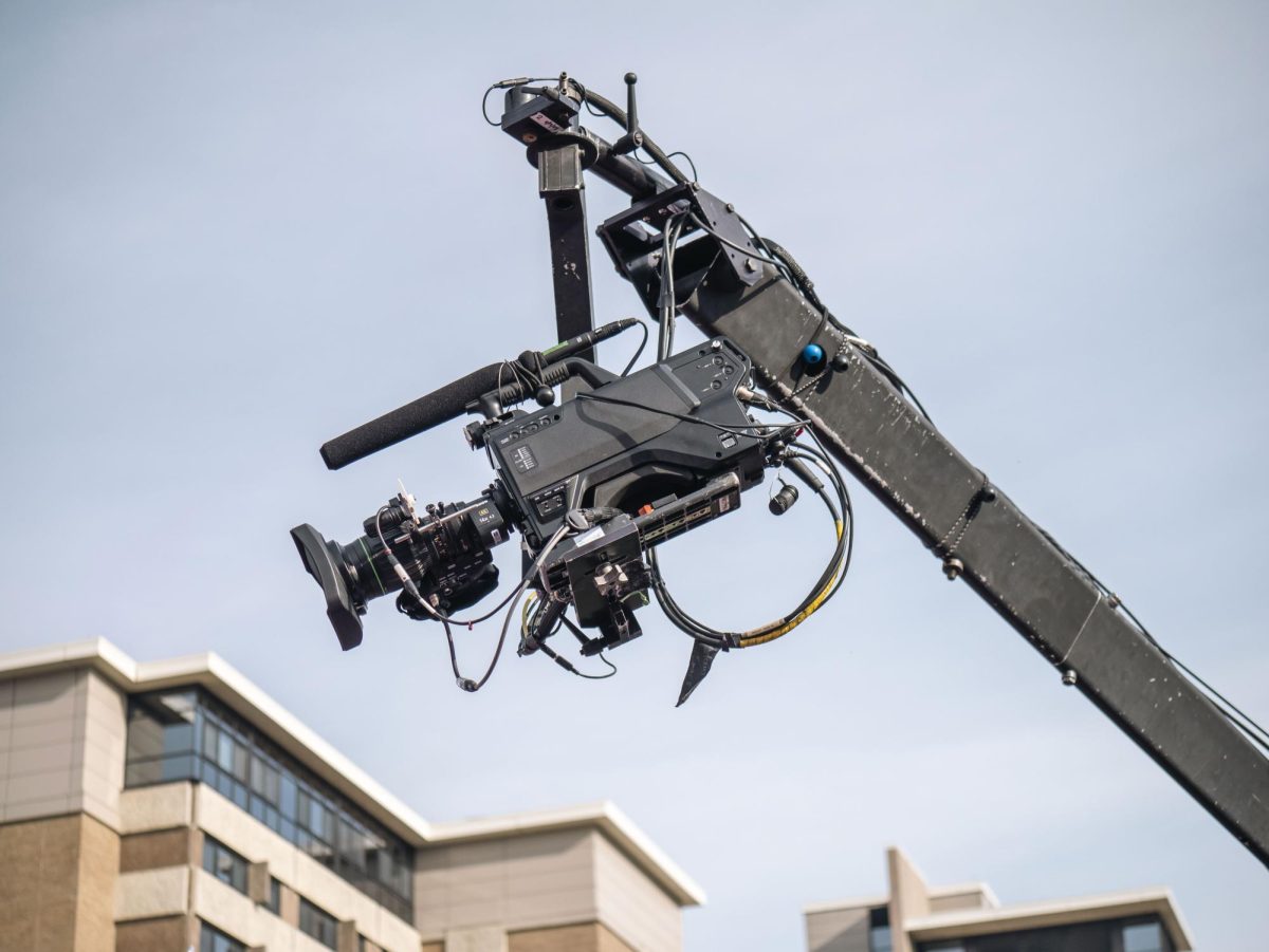 Broadcast camera on crane swings over the Kohl Center lawn. 