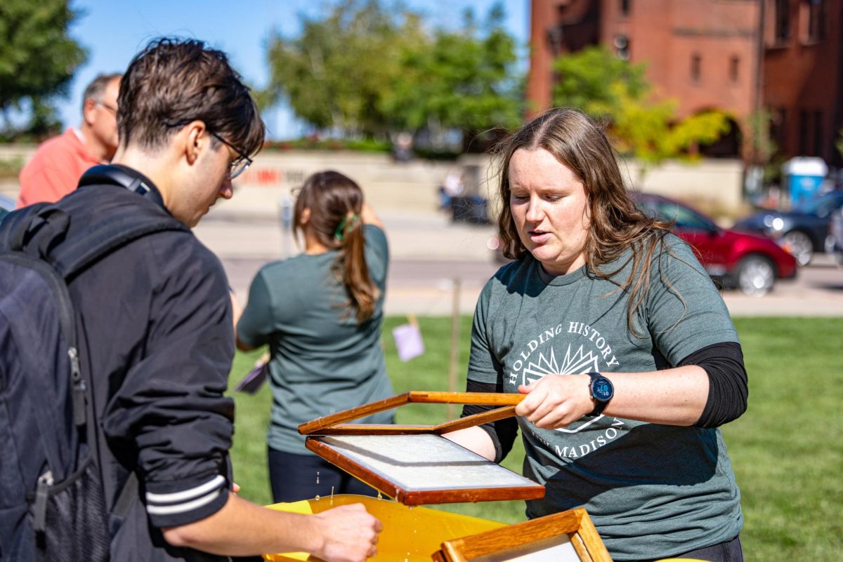 Holding History volunteer and graduate student Kristen Diederichs demonstrates the paper making process to students passing by at Library Mall. October 1, 2024.