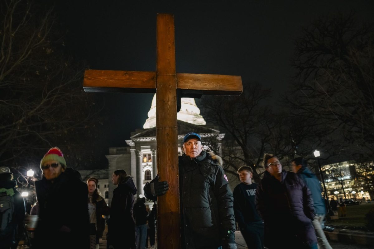 Crowd member props up a cross at the Abundant Life Christian school shooting vigil. December 17, 2024.